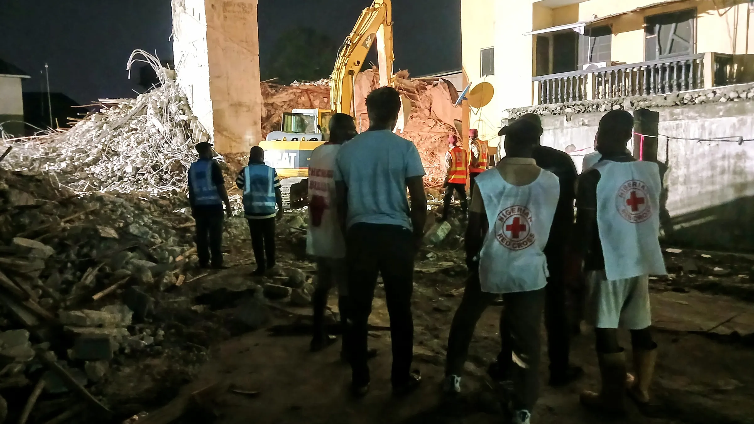 Rescue workers beside the rubble, with a concrete core still standing