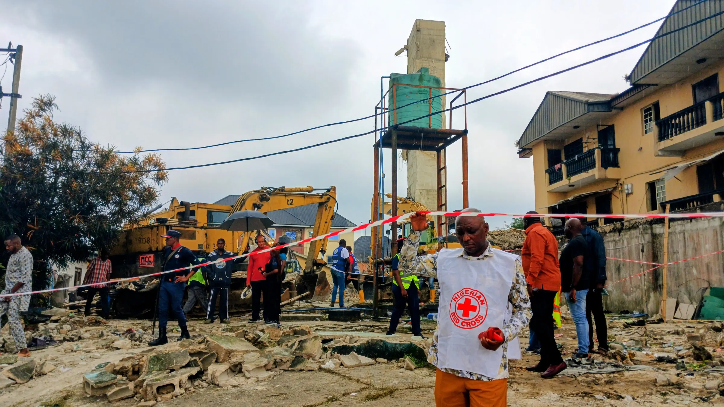 The collapse site in daylight, cordoned off, with excavators and a standing concrete core
