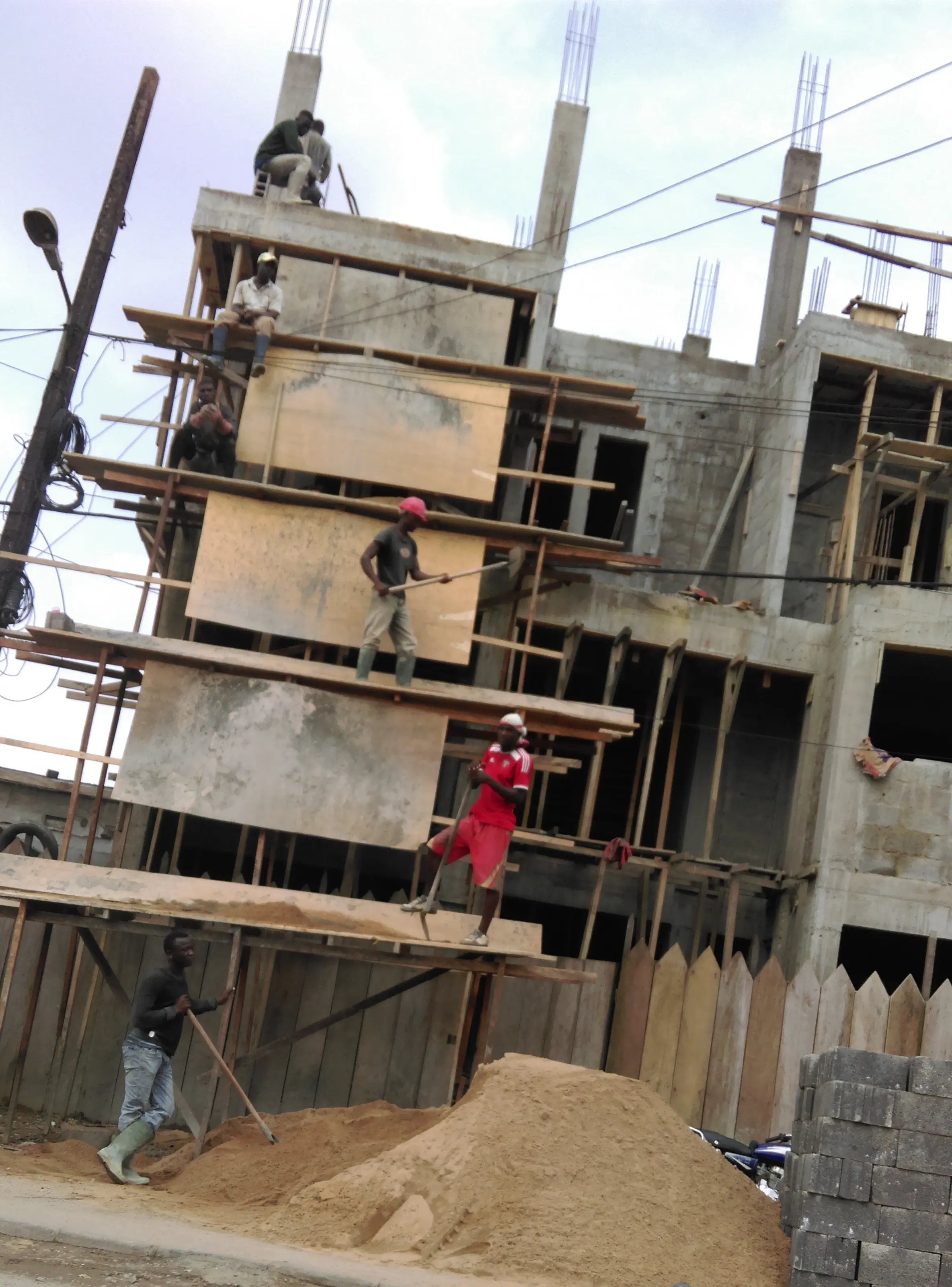 Workers on timber formwork at height on a multi-storey building in Douala