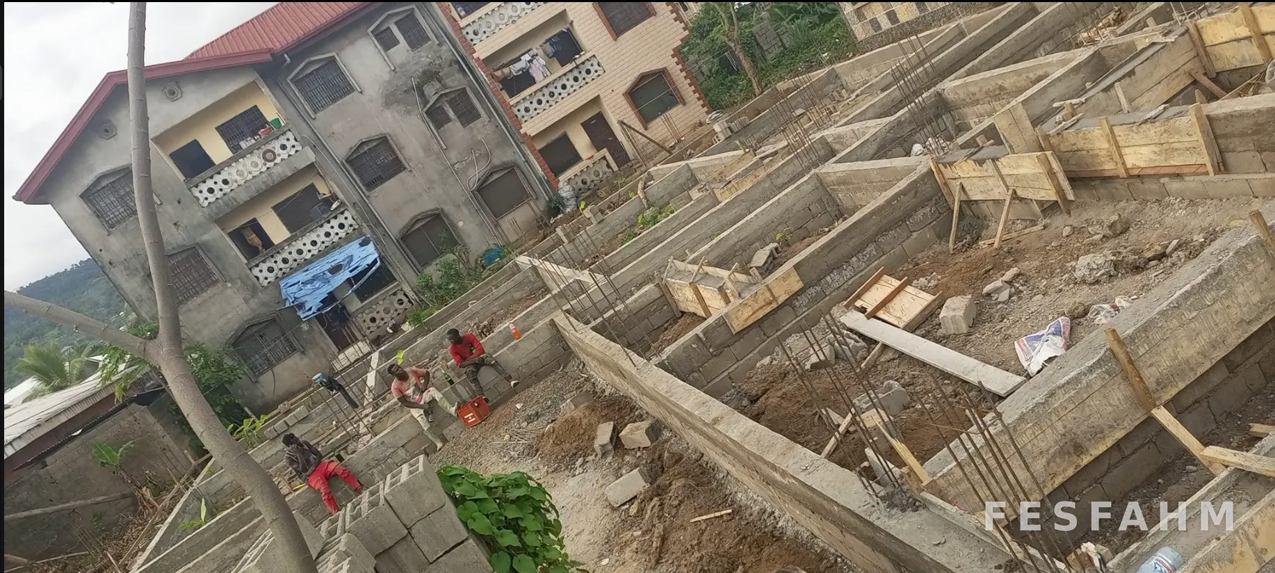 Foundation works with cement-block foundation walls, timber formwork for ground beams, starter bars and workers on site